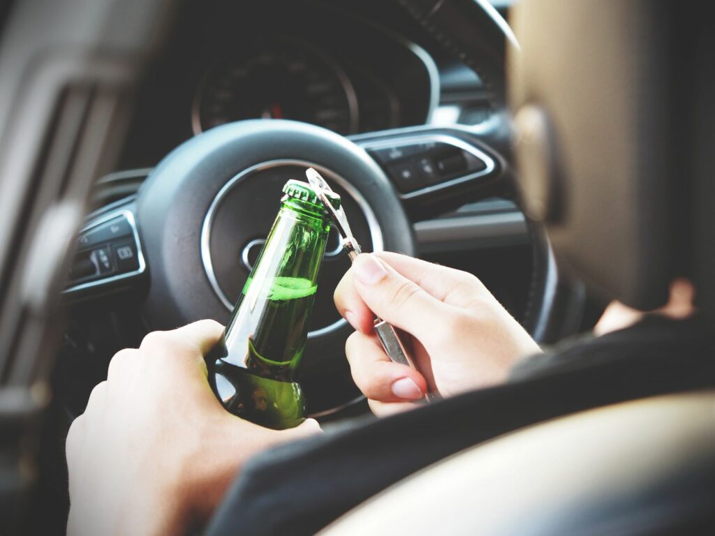 Conducteur tenant une bouteille de bière au volant, illustration de l'alcool au volant