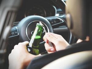 Conducteur tenant une bouteille de bière au volant, illustration de l'alcool au volant