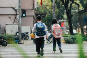 two children crossing street with backpacks